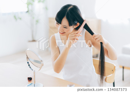 A young woman using a hair iron 134087373