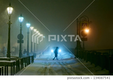 Dramatic Night Winter Landscape with Fog, Snowfall, and Vintage Street Lamps Dramatic Night Winter Landscape with Fog, Snowfall, and Vintage Street Lamps 134087541