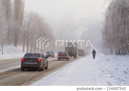Snow-Covered Slippery City Road and Truck in Snowfall and Poor Visibility Conditions 134087542