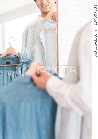 一位年輕的亞裔男子正在照鏡子搭配衣服。 134087631