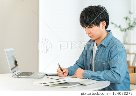 一位認真負責的年輕亞裔男子在家學習，以提高自己的技能（自我投資、管理、家庭學習）。 134088272