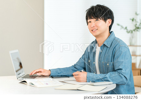 一位認真負責的年輕亞裔男子在家學習，以提高自己的技能（自我投資、管理、家庭學習）。 134088276