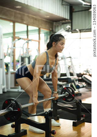 Photo set of sportive serious woman lifting barbells in gym Photo set of sportive serious woman lifting barbells in gym 134089063