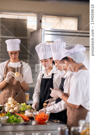 Asian female chef and her students or assistant peeling onions together at kitchen cooking counter. Asian female chef and her students or assistant peeling onions together at kitchen cooking counter. 134089618