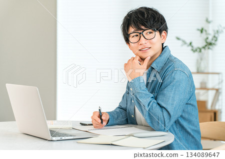 一位認真負責的年輕亞裔男子在家學習，以提高自己的技能（自我投資、管理、家庭學習）。 134089647