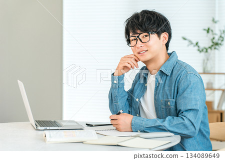 一位認真負責的年輕亞裔男子在家學習,以提高自己的技能(自我投資、管理、家庭學習)。 一位認真負責的年輕亞裔男子在家學習,以提高自己的技能(自我投資、管理、家庭學習)。 134089649