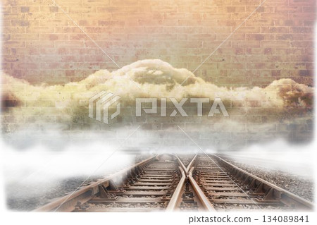 Train tracks leading to brick wall with clouds 134089841