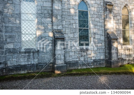 Flat design is depicting stone wall exterior with pointed-arch windows, buttresses, gravel path 134090094