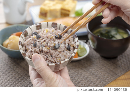 用筷子享用日式什錦米飯早餐,以及溫馨的用餐場景。 用筷子享用日式什錦米飯早餐,以及溫馨的用餐場景。 134090486