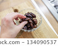 Hand picking dried date fruit from glass bowl 134090537
