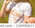 Girl child staining her white t-shirt with stain while enjoying a delicious chocolate bar in garden 134090623