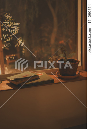 a pile of books and small pots on a wooden window sill 134090834
