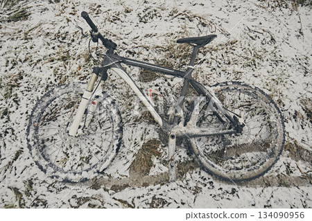 Bicycle in snow and mud in winter against the background of grass 134090956
