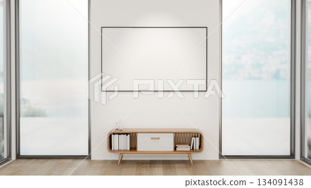 Blank frame over a table between two glass doors of a wooden floor room with snowy scenery outside. Blank frame over a table between two glass doors of a wooden floor room with snowy scenery outside. 134091438