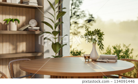 A coffee cup and books on a wooden round table with chairs inside a room with nature view outside. A coffee cup and books on a wooden round table with chairs inside a room with nature view outside. 134091446