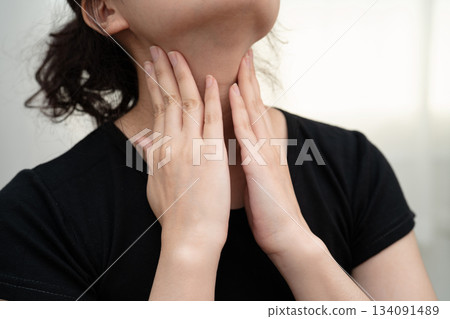 Asian woman touching her neck and throat for thyroid gland problem. 134091489