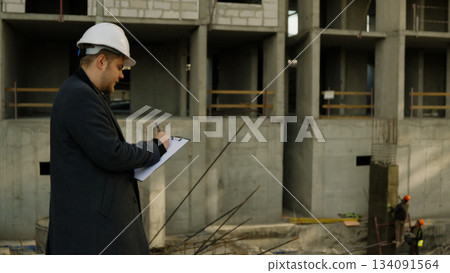 Male engineer looking at blueprints on a tablet at the active construction site Male engineer looking at blueprints on a tablet at the active construction site 134091564