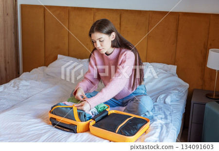 Young woman packing suitcase for upcoming travel journey Young woman packing suitcase for upcoming travel journey 134091603
