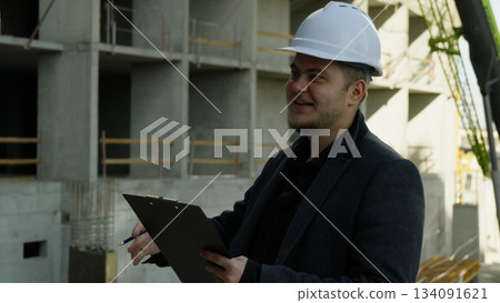 Male engineer looking at blueprints on a tablet at the active construction site 134091621
