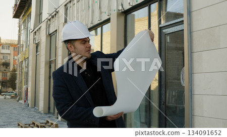 Engineer-architect holding plans on a construction site Engineer-architect holding plans on a construction site 134091652