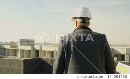 Male engineer-architect overseeing construction progress from the roof Male engineer-architect overseeing construction progress from the roof 134091686