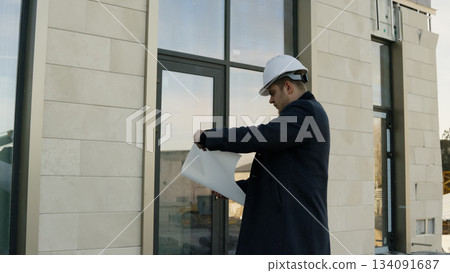 Male engineer reviewing building plans on a digital tablet at the construction Male engineer reviewing building plans on a digital tablet at the construction 134091687