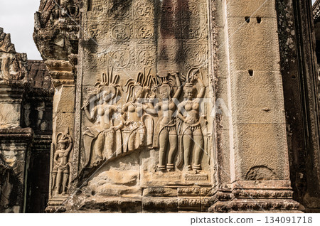 Detailed stone bas-relief depicting group of four Apsara celestial dancers on exterior wall of ancient Khmer temple in Siem Reap 134091718