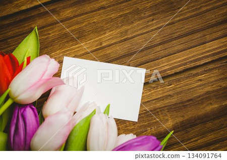 blank white rectangular card is lying atop wooden tabletop in flat-lay, with colorful tulip bouquet blank white rectangular card is lying atop wooden tabletop in flat-lay, with colorful tulip bouquet 134091764