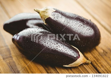 Wet eggplants on wooden floor 134091822