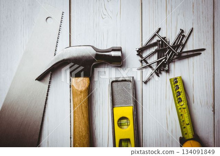 Flat design is showing carpentry tools, hammer, saw, level, nails and tape measure on wooden plank Flat design is showing carpentry tools, hammer, saw, level, nails and tape measure on wooden plank 134091849