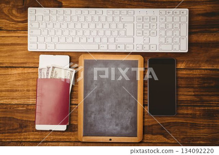 Flat top-down view showing chalkboard slate between keyboard, passport, US dollar bills, smartphone Flat top-down view showing chalkboard slate between keyboard, passport, US dollar bills, smartphone 134092220
