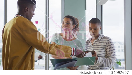 Man in mustard jacket handing documents as team reviewing at office window, with clipboard, phone Man in mustard jacket handing documents as team reviewing at office window, with clipboard, phone 134092607