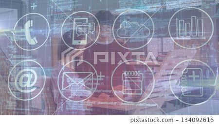 Two coworkers collaborating at office desk, reviewing code overlay on laptop with digital icons 134092616