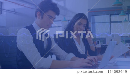 Typing professionals in suits working at desk in office, with laptop smartphone printed documents Typing professionals in suits working at desk in office, with laptop smartphone printed documents 134092649