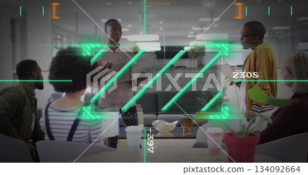 Presenting dual-heritage woman gesturing with laptop in office lounge, with tablet coffee mugs 134092664