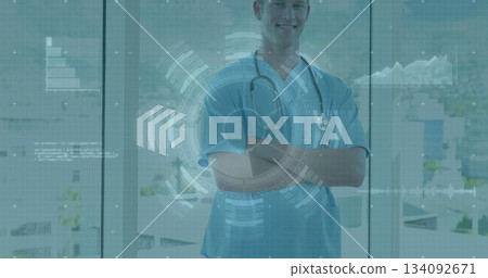 Standing physician wearing scrubs, stethoscope before large glass windows, showing digital overlays 134092671