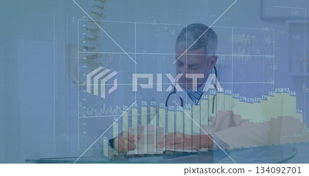 Reviewing and writing physician in lab coat with stethoscope at desk, spine model and data overlays Reviewing and writing physician in lab coat with stethoscope at desk, spine model and data overlays 134092701