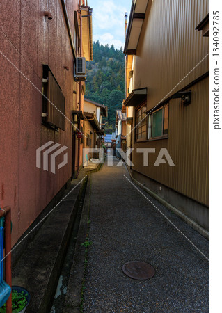 郡上八幡的傍晚街景，一條狹窄的小巷盡頭，房屋林立，遠處可見群山。 134092785