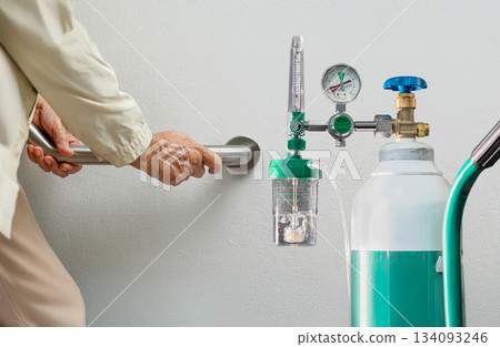 Elderly woman walking to emergency medical oxygen tank. 134093246