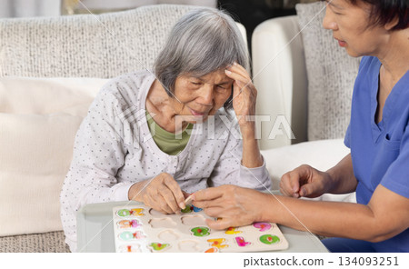 Nurse in nursing home helping a senior woman with number puzzle.  . Dementia, Alzheimer's disease concept 134093251