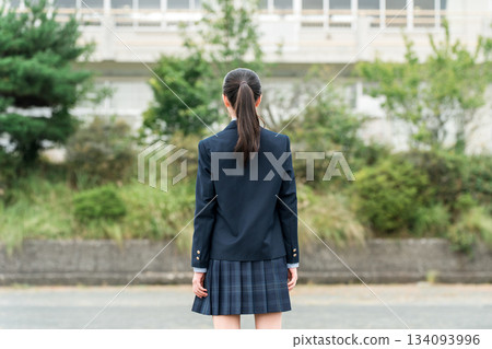 Back view of junior high school, high school, and elementary school students in uniform standing in front of a school building Back view of junior high school, high school, and elementary school students in uniform standing in front of a school building 134093996