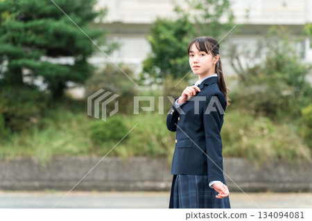 Junior high school, high school, and elementary school students in uniform standing in front of the school building 134094081