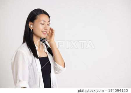 Smiling woman wearing wireless earphones 134094130