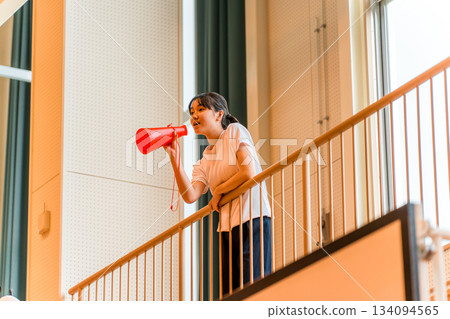 一名身穿運動服的女學生在體育館裡用擴音器歡呼（加油，加油，加油，加油） 134094565