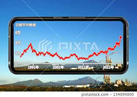 智慧型手機螢幕的圖片，以山脈和工廠的鏤空風景作為壁紙，顯示長期股票價格趨勢。 134094800