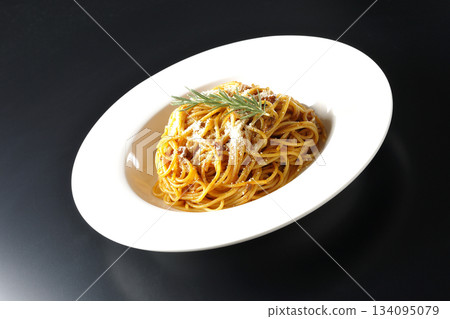 義大利麵肉醬配碎起司和迷迭香,以黑色背景拍攝。 義大利麵肉醬配碎起司和迷迭香,以黑色背景拍攝。 134095079