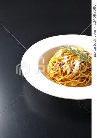 Spaghetti meat sauce with grated cheese and rosemary photographed against a black background 134095096
