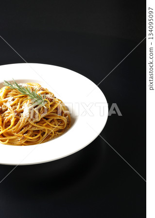 Spaghetti meat sauce with grated cheese and rosemary photographed against a black background 134095097