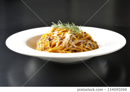 Spaghetti meat sauce with grated cheese and rosemary photographed against a black background Spaghetti meat sauce with grated cheese and rosemary photographed against a black background 134095098