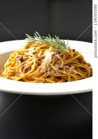 Spaghetti meat sauce with grated cheese and rosemary photographed against a black background Spaghetti meat sauce with grated cheese and rosemary photographed against a black background 134095099